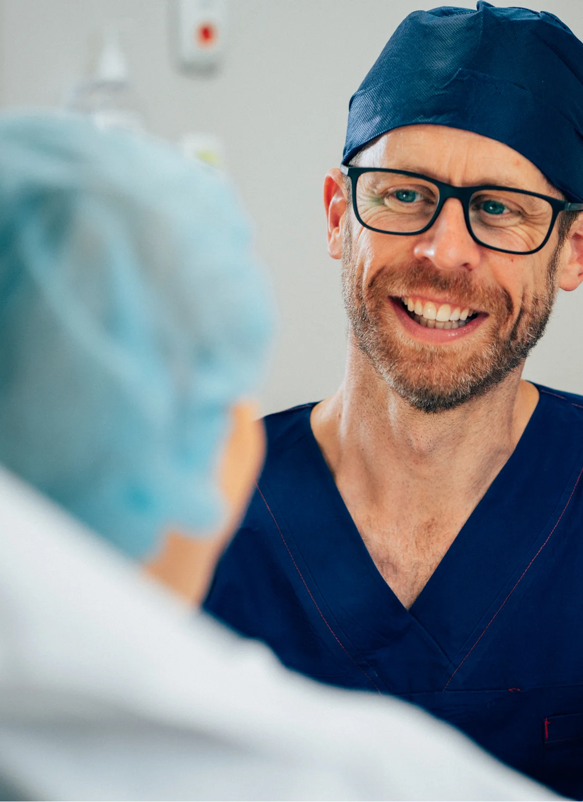 Dr Anthony Barker in scrubs and glasses speaking with healthcare colleague in medical setting - in New South Wales, Australia